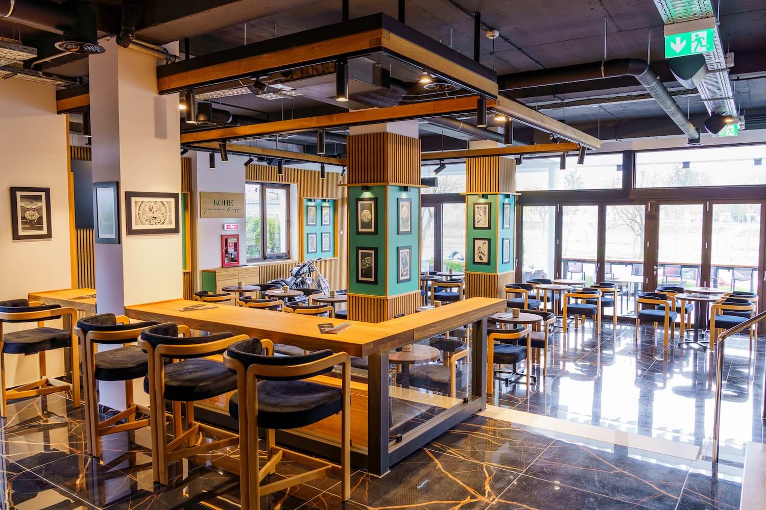 Interiorul cafenelei Kohe, cu mese de lemn și accente verzi